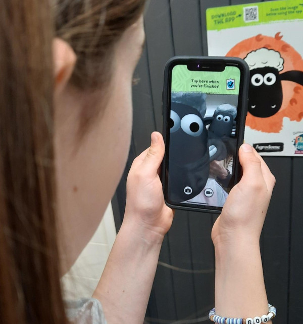 girl holding a phone with Shaun the Sheep interactive app displayed on the screen